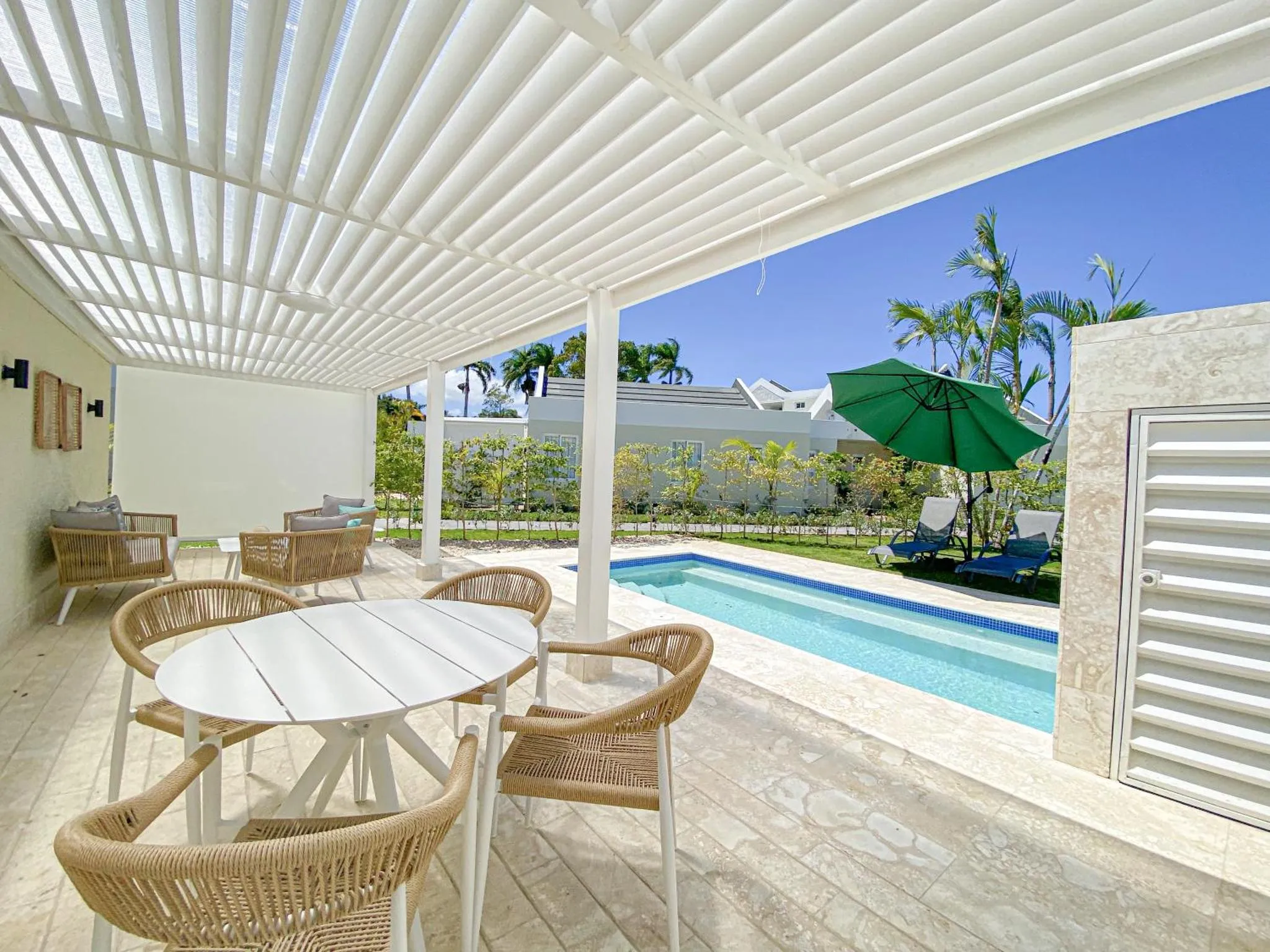 Terrasse ombragée avec mobilier de jardin et piscine.