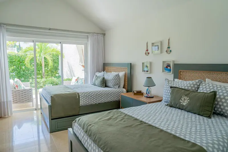Une chambre lumineuse avec deux lits et une vue sur un jardin tropical.