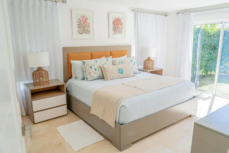 Une chambre lumineuse avec un grand lit recouvert d'une courtepointe et de coussins.