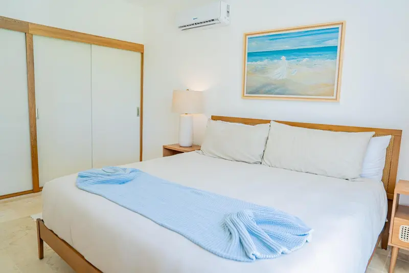 Une chambre lumineuse avec un grand lit recouvert d'une couverture bleue.