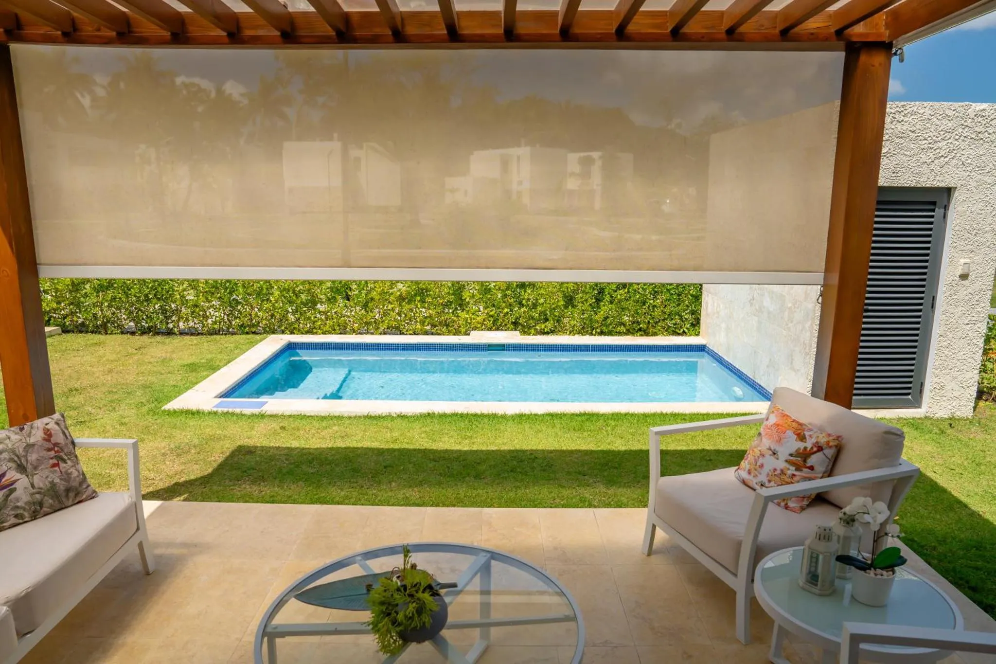 Terrasse ombragée donnant sur une petite piscine et un jardin verdoyant.