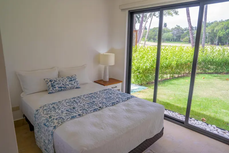 Une chambre lumineuse avec un grand lit et une vue sur un jardin verdoyant.