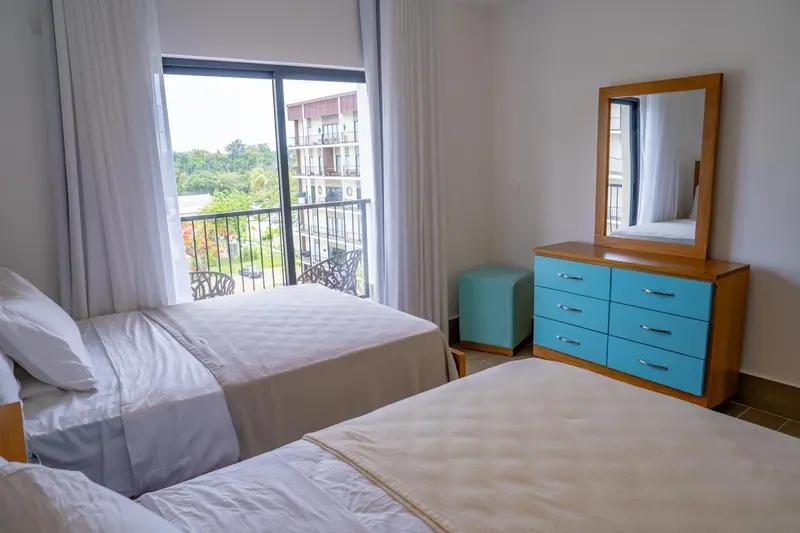 Une chambre lumineuse avec deux lits et une commode turquoise.