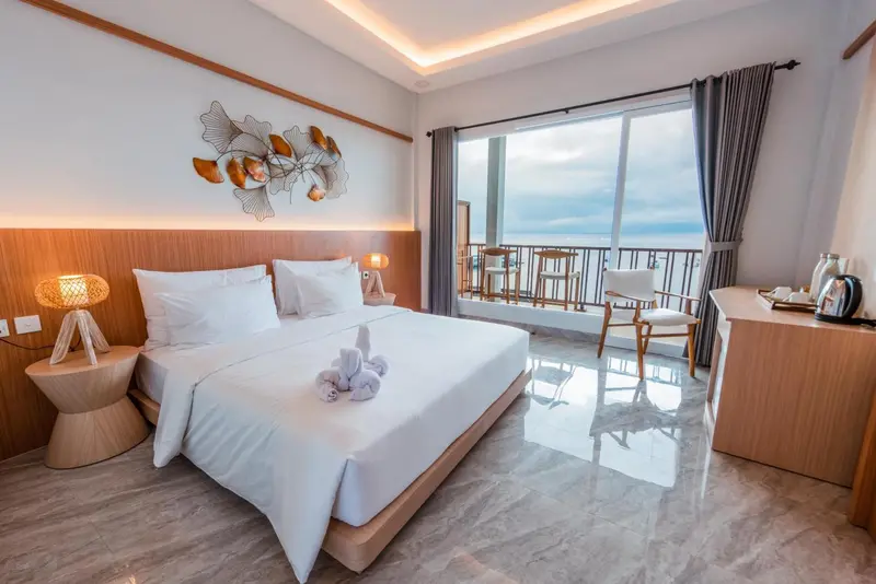 Une chambre lumineuse avec un grand lit et un accès à un balcon.