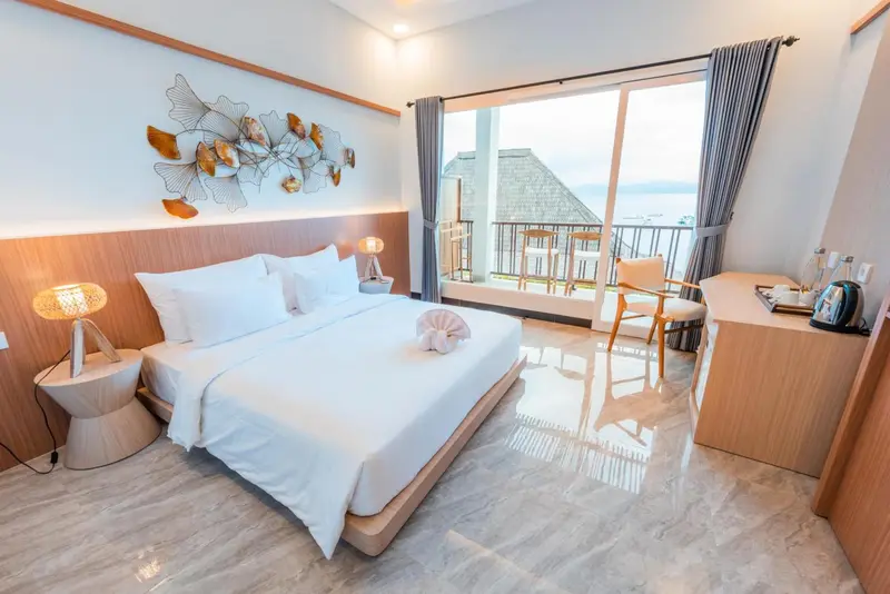 Chambre lumineuse avec un grand lit et une vue sur la mer.