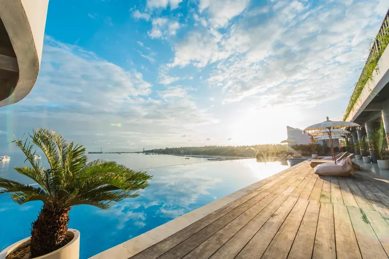 Une piscine à débordement offre une vue sur la mer et le ciel nuageux.