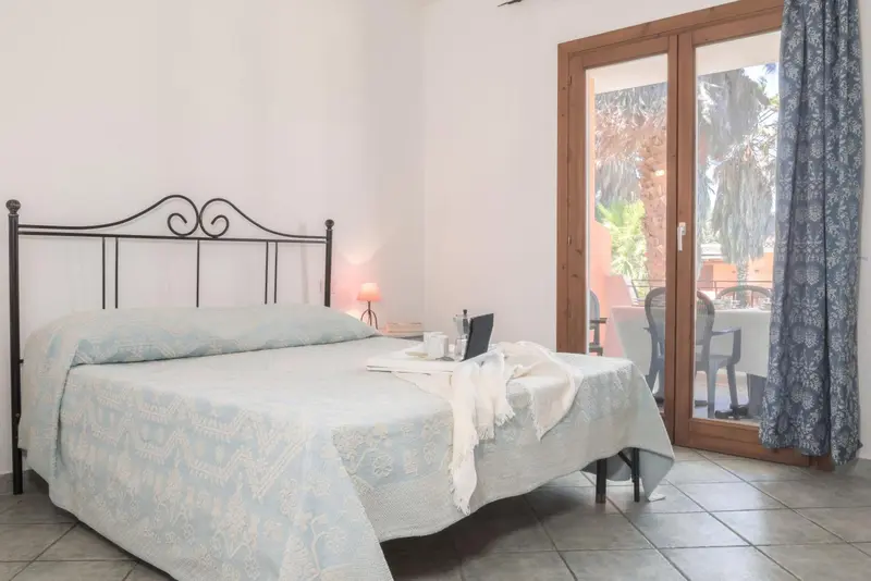 Une chambre lumineuse avec un lit fait et une vue sur l'extérieur.