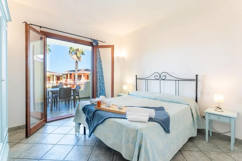 Chambre lumineuse avec un lit recouvert d'une couverture bleue et une table de chevet.