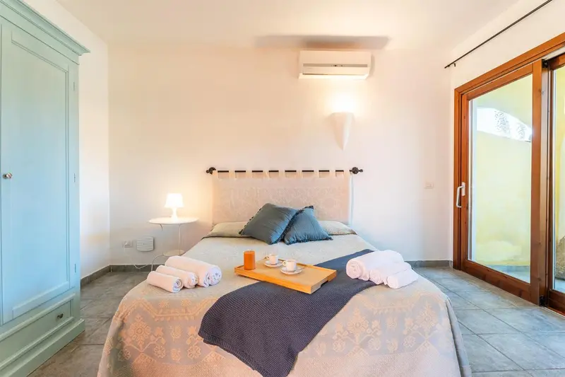 Une chambre lumineuse avec un lit fait et une armoire.