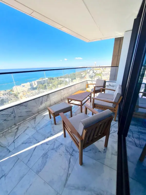 Terrasse aménagée avec mobilier de jardin et vue sur la mer.