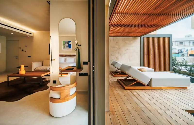 Espace de vie intérieur avec canapé et accès à une terrasse en bois avec chaises longues.