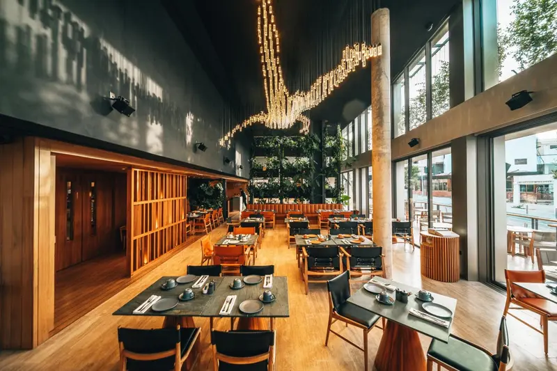 Une salle lumineuse avec des tables dressées pour un repas.