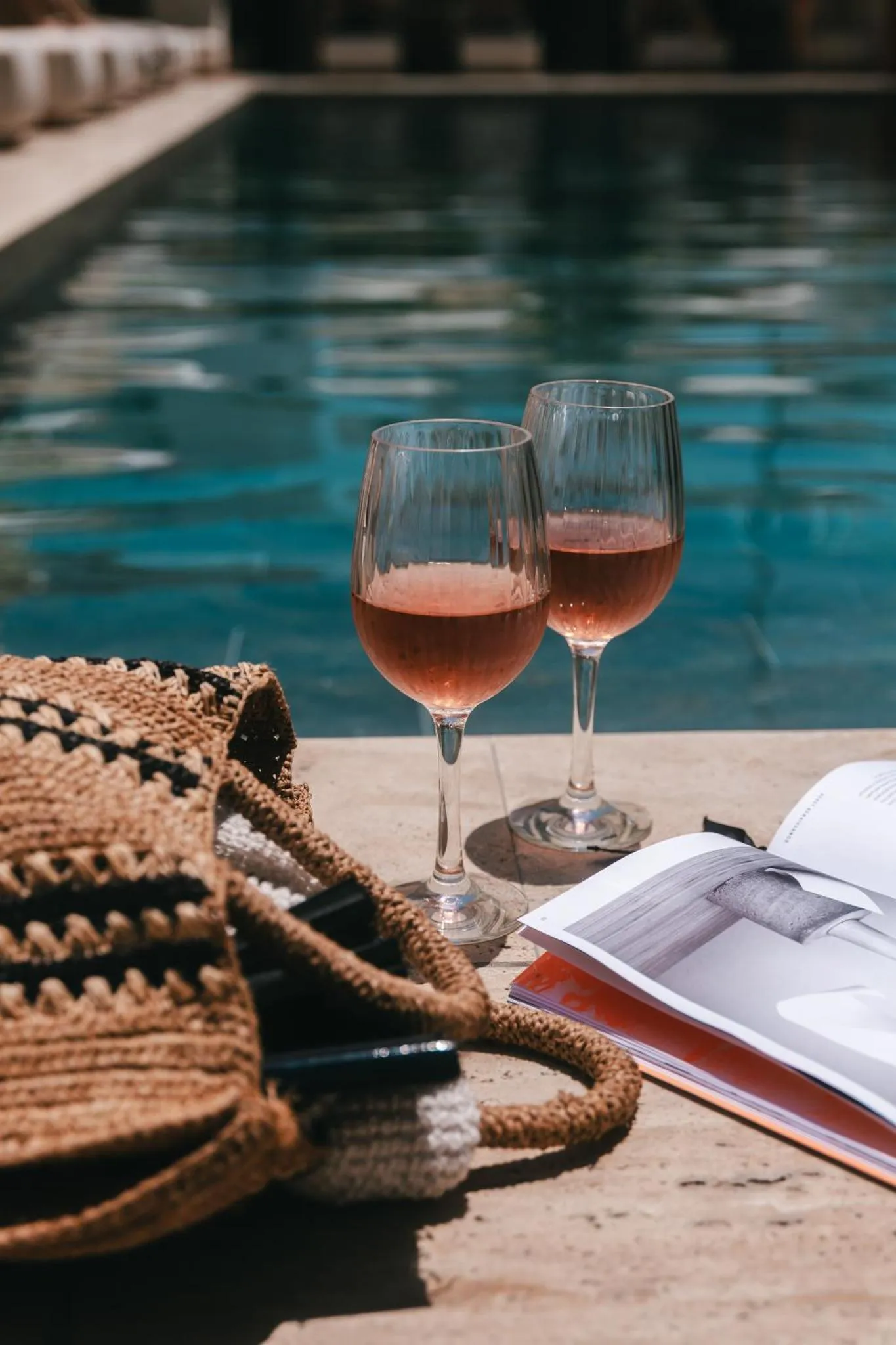 Deux verres de boisson rafraîchissante reposent au bord d'une piscine ensoleillée.
