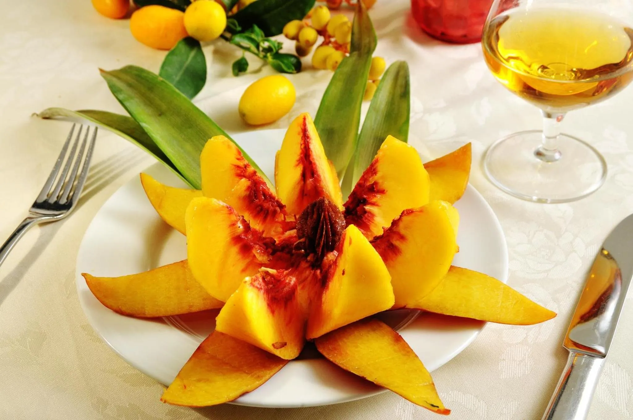 Une assiette de fruits exotiques sculptés est présentée sur une table nappée.
