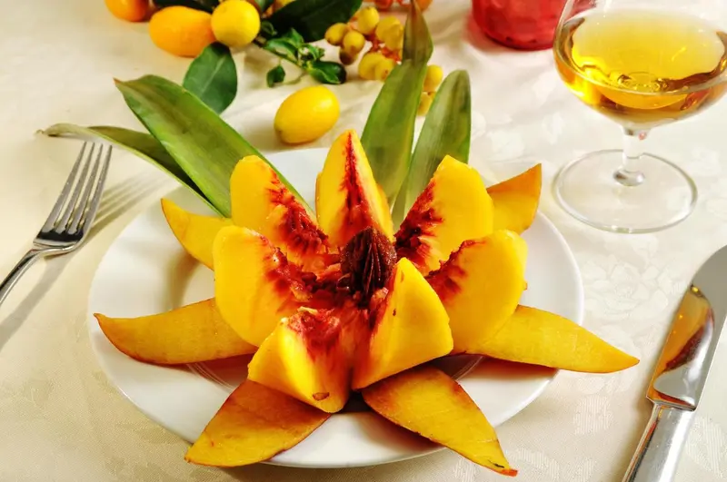 Une assiette de fruits exotiques sculptés est présentée sur une table nappée.