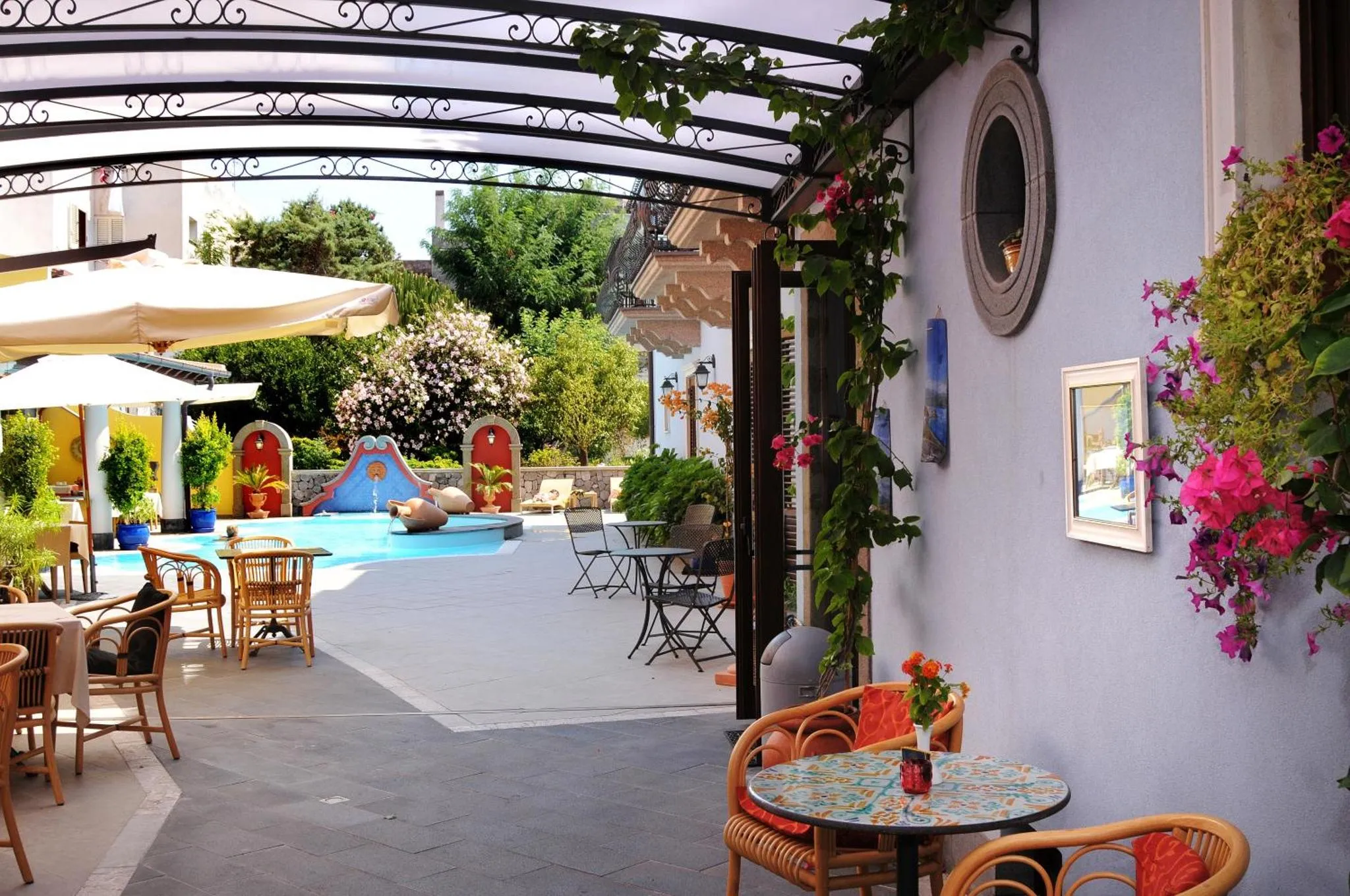 Terrasse ombragée donnant sur une piscine et un espace de détente extérieur.