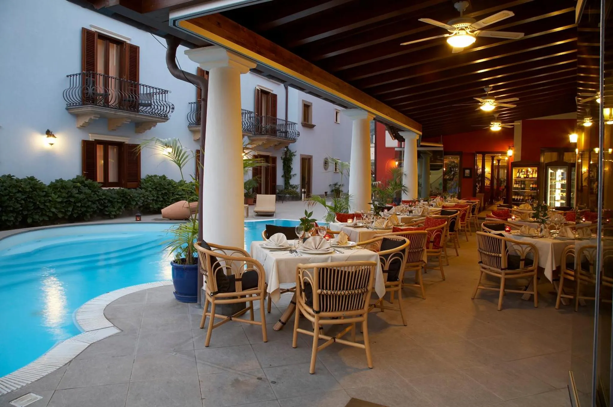 Une terrasse ombragée avec des tables dressées près d'une piscine.