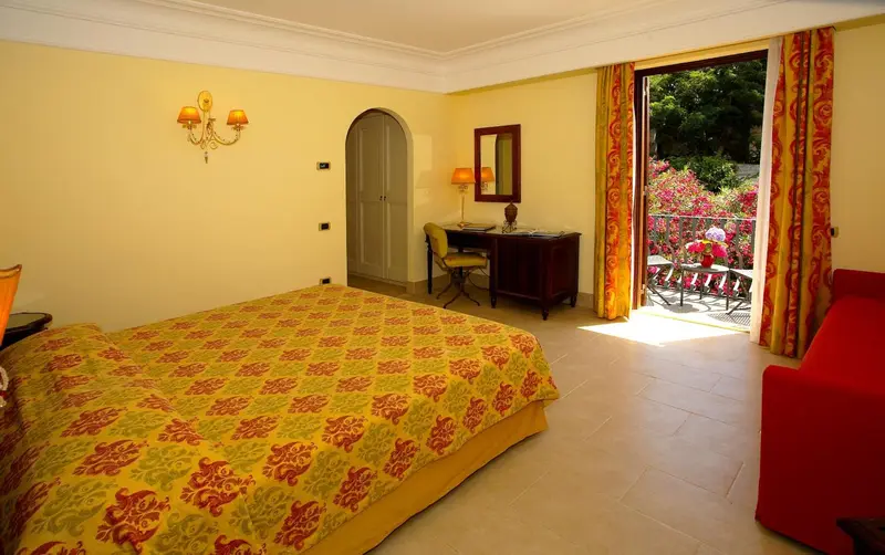 Une chambre lumineuse avec un lit recouvert d'une courtepointe colorée et un accès à un balcon.