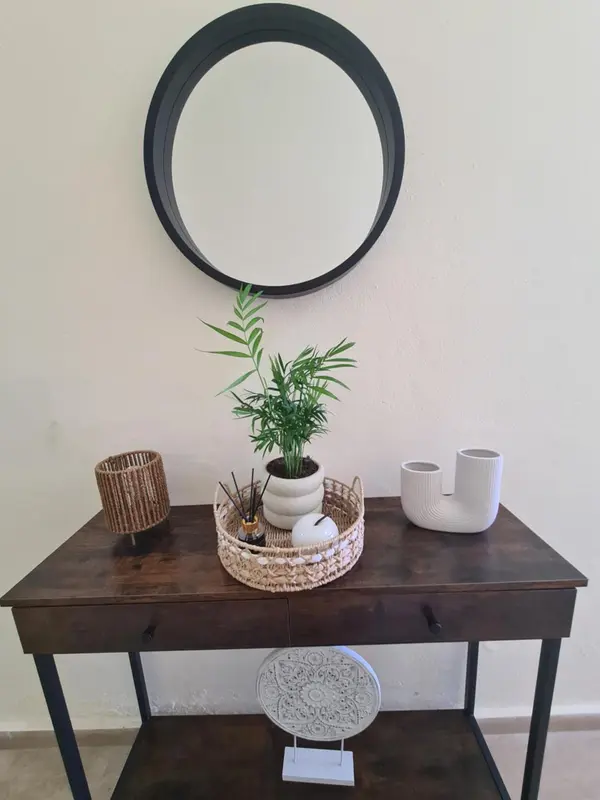 Une console en bois sombre ornée d'un miroir rond et de divers objets décoratifs.
