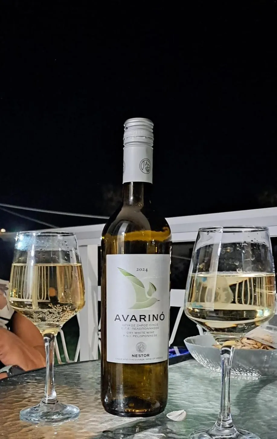 Une bouteille de vin blanc et deux verres à vin sont posés sur une table.