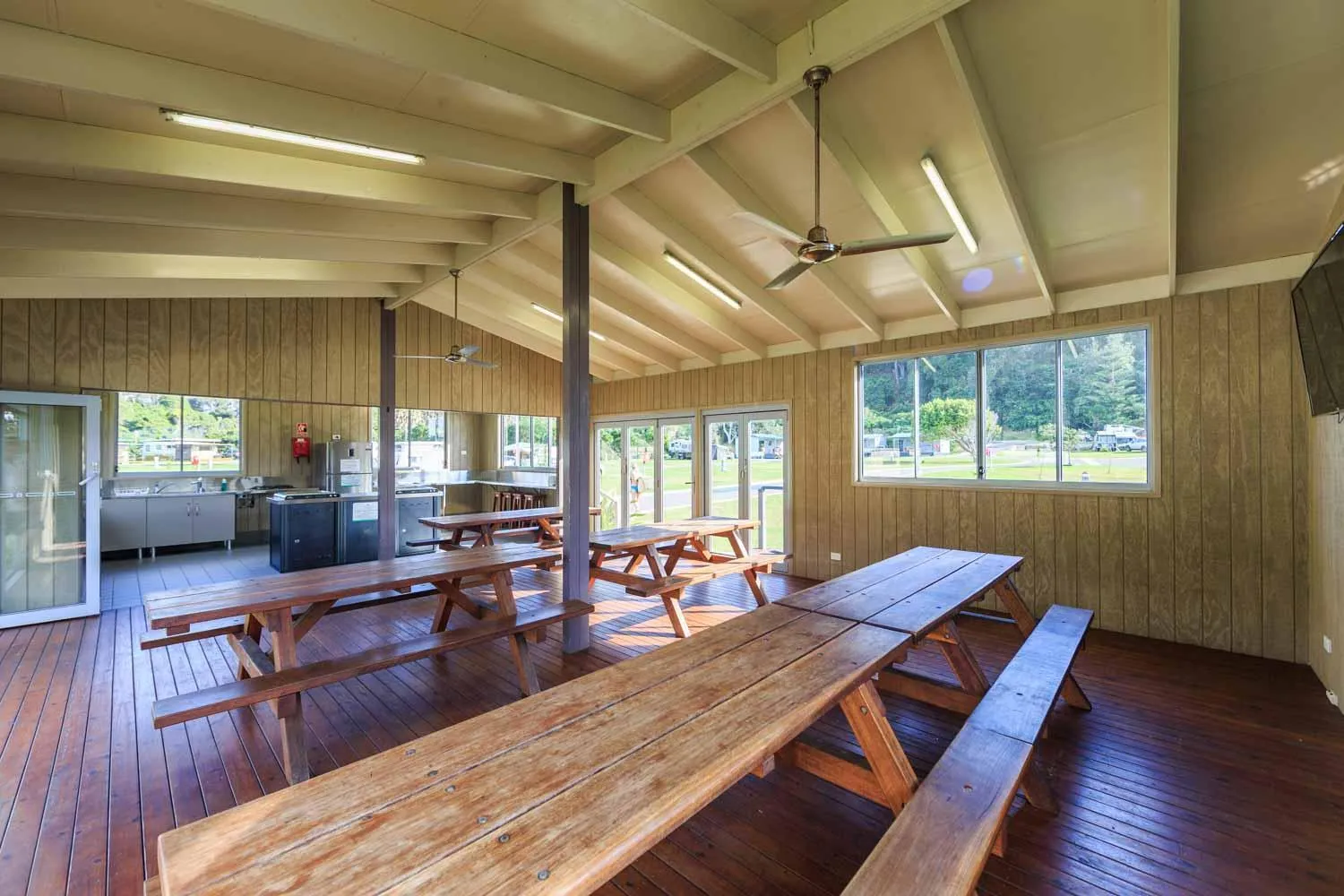 Une salle ouverte sur un espace extérieur avec des tables et des bancs en bois.