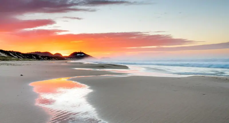Une plage de sable fin baignée par les vagues au coucher du soleil.