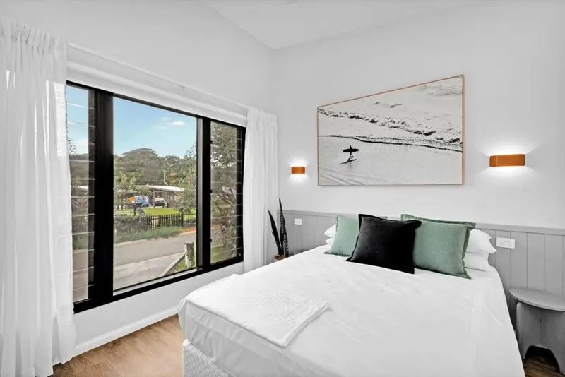 Une chambre lumineuse avec un grand lit et une vue sur un jardin verdoyant.