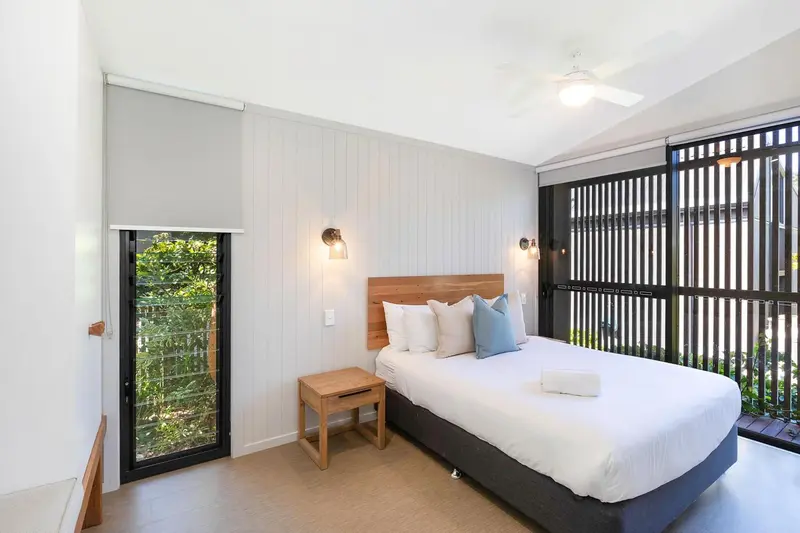 Une chambre lumineuse avec un grand lit et une fenêtre donnant sur la végétation.