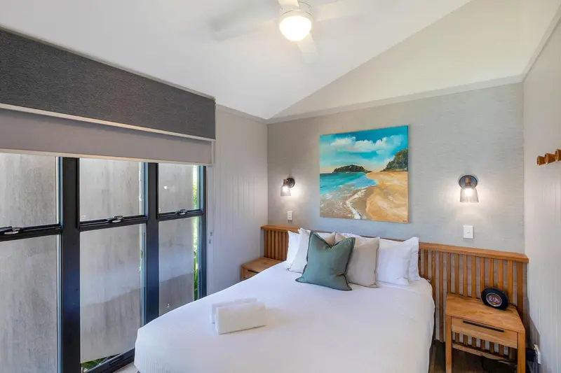 Une chambre lumineuse avec un grand lit et une décoration murale représentant une plage.