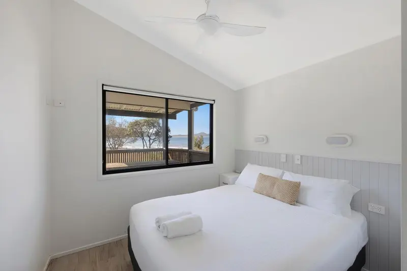 Une chambre lumineuse avec un grand lit et une vue sur la mer par la fenêtre.