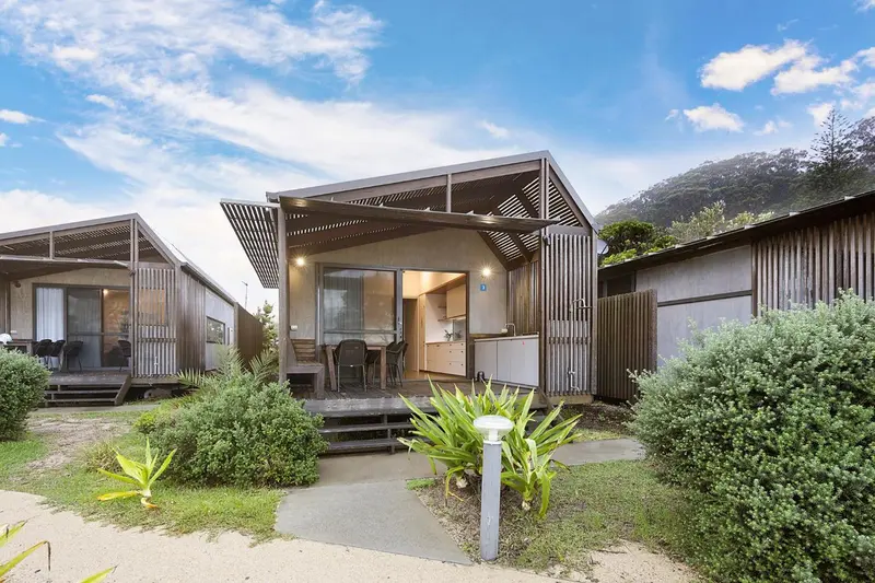 Logements modernes en bois avec terrasses et mobilier de jardin.