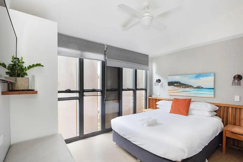Une chambre lumineuse avec un grand lit et une décoration murale.