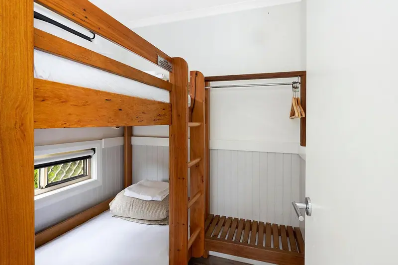 Une chambre avec un lit superposé en bois et un placard intégré.