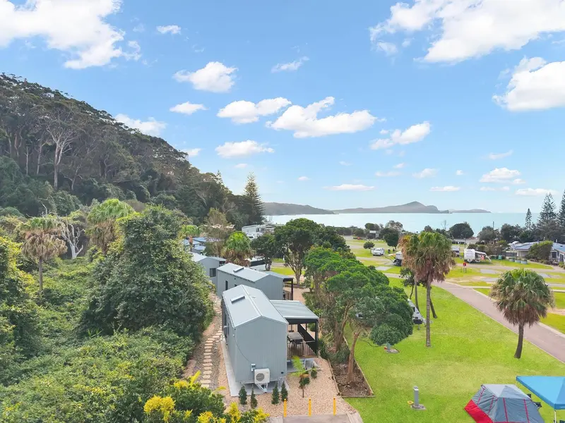 Vue aérienne d'un parc de chalets et de camping verdoyant près de la mer.