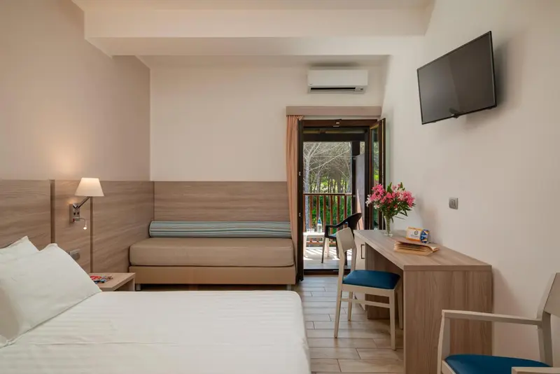 Une chambre lumineuse avec un lit et un bureau donnant sur une terrasse.