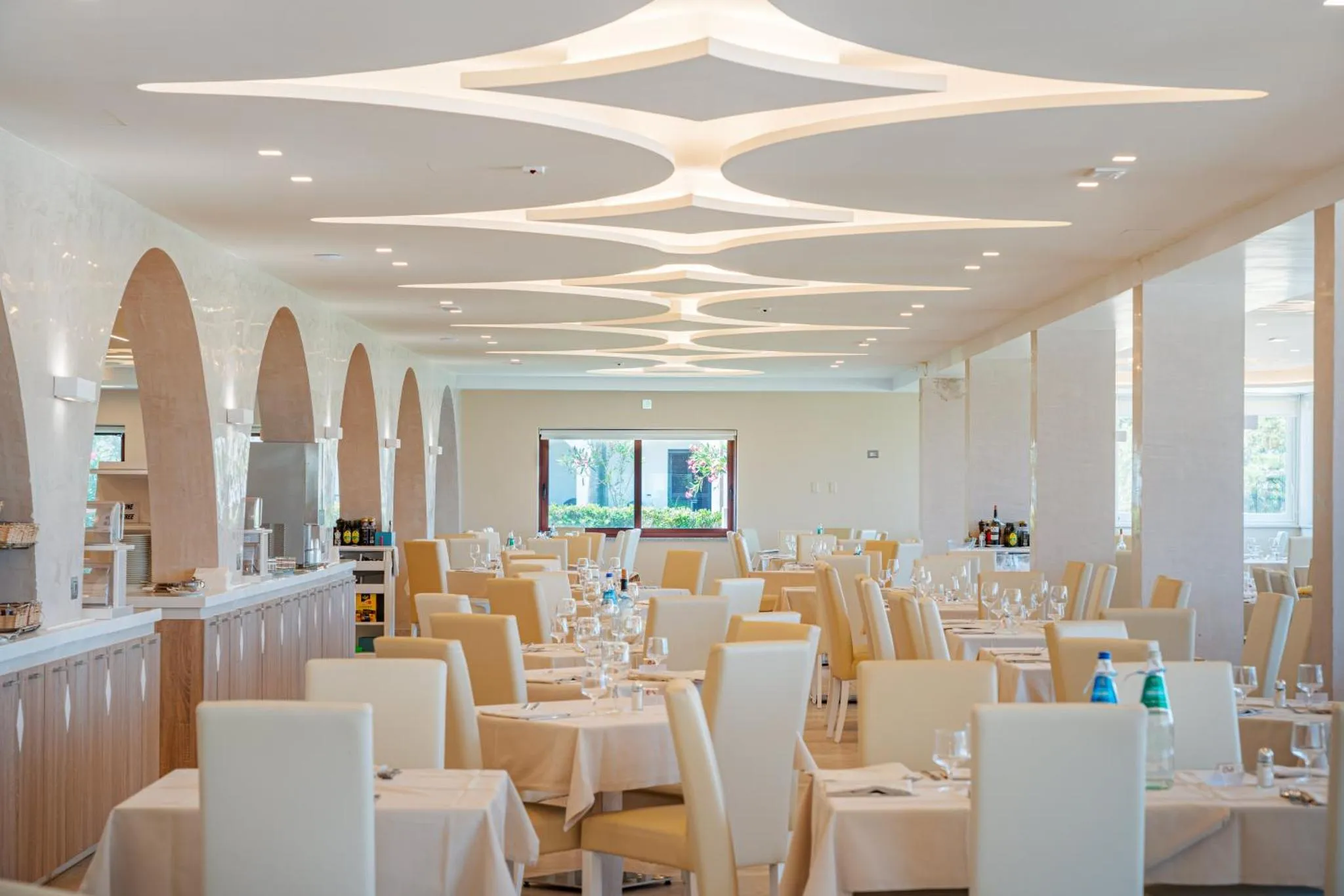 Une salle lumineuse avec des tables dressées pour un repas.