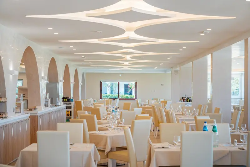 Une salle lumineuse avec des tables dressées pour un repas.