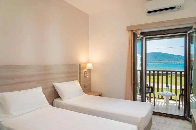 Une chambre lumineuse avec un lit simple donnant sur une vue mer.