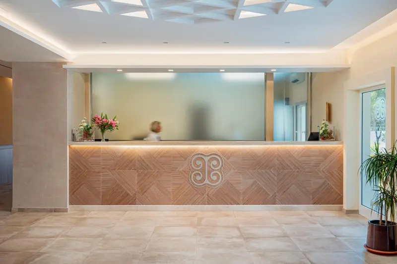 Un comptoir d'accueil moderne avec un décor en bois clair et des fleurs.