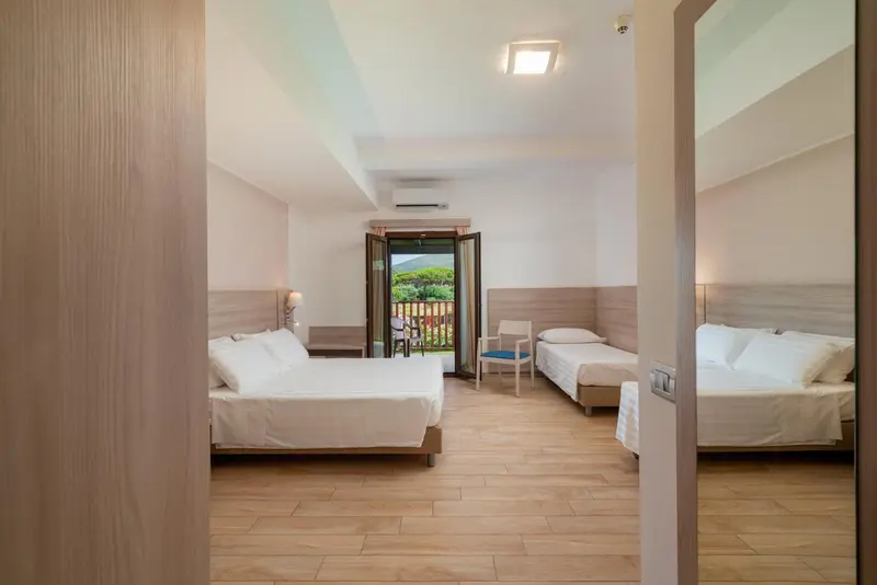 Chambre lumineuse avec deux lits simples et vue sur un paysage verdoyant.