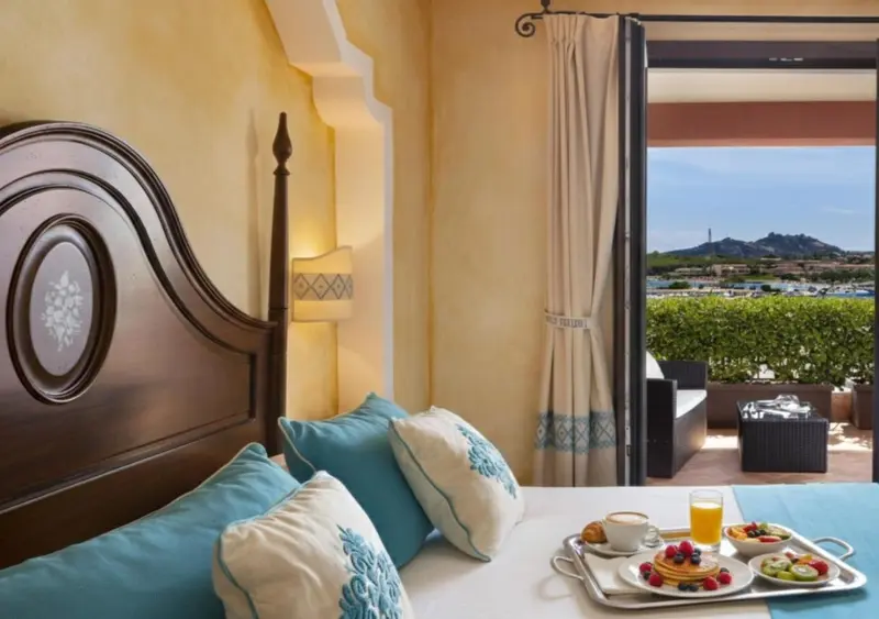 Une chambre lumineuse avec un lit décoré et un plateau de petit-déjeuner sur une table.