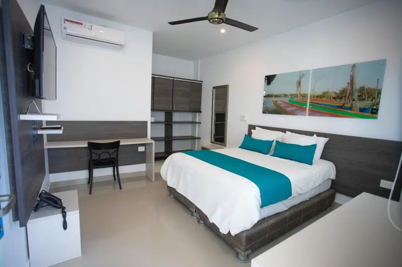 Une chambre moderne avec un grand lit recouvert d'une literie turquoise et un bureau.