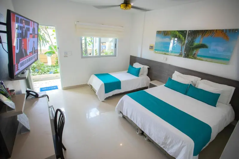 Chambre lumineuse avec deux lits simples et une décoration murale tropicale.