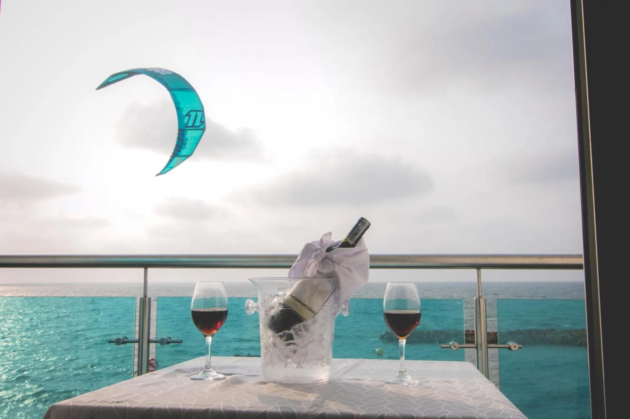 Une table avec des verres de vin et une bouteille fraîche face à l'océan.