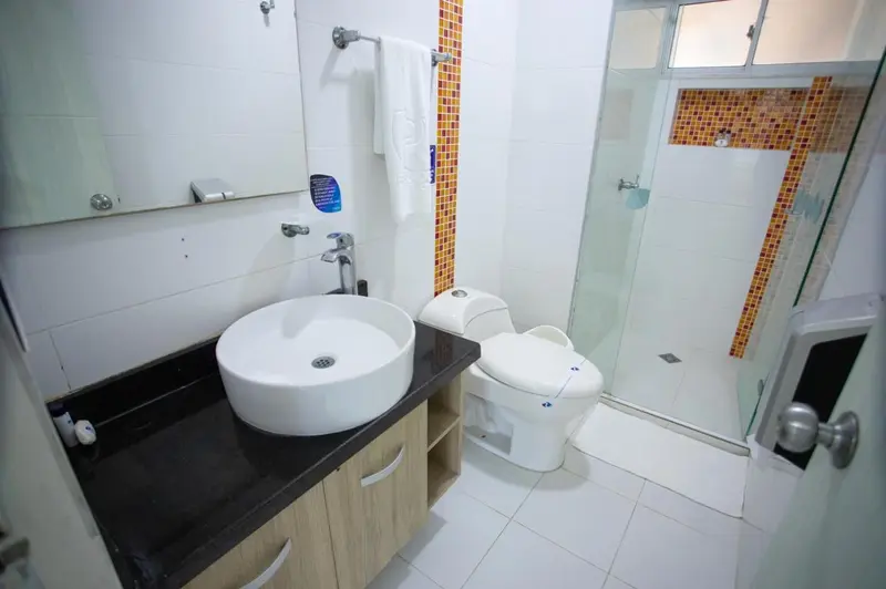 Une salle de bain claire avec douche à l'italienne et lavabo sur meuble.
