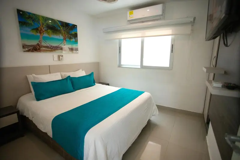 Une chambre lumineuse avec un grand lit recouvert d'une courtepointe turquoise.
