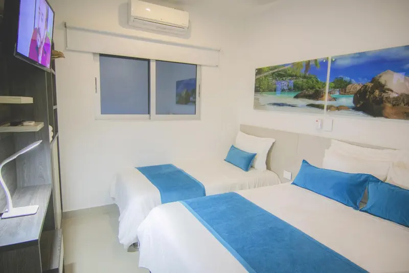 Une chambre lumineuse avec deux lits simples et une décoration murale tropicale.