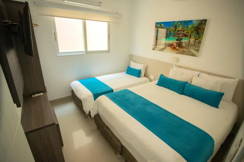 Chambre lumineuse avec deux lits simples et une décoration murale tropicale.