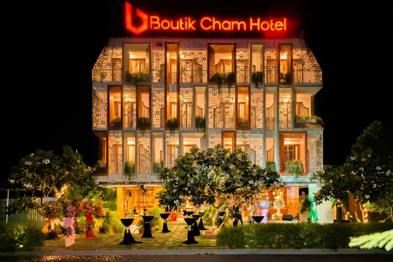 Façade d'un bâtiment illuminé avec des arbustes décoratifs devant.