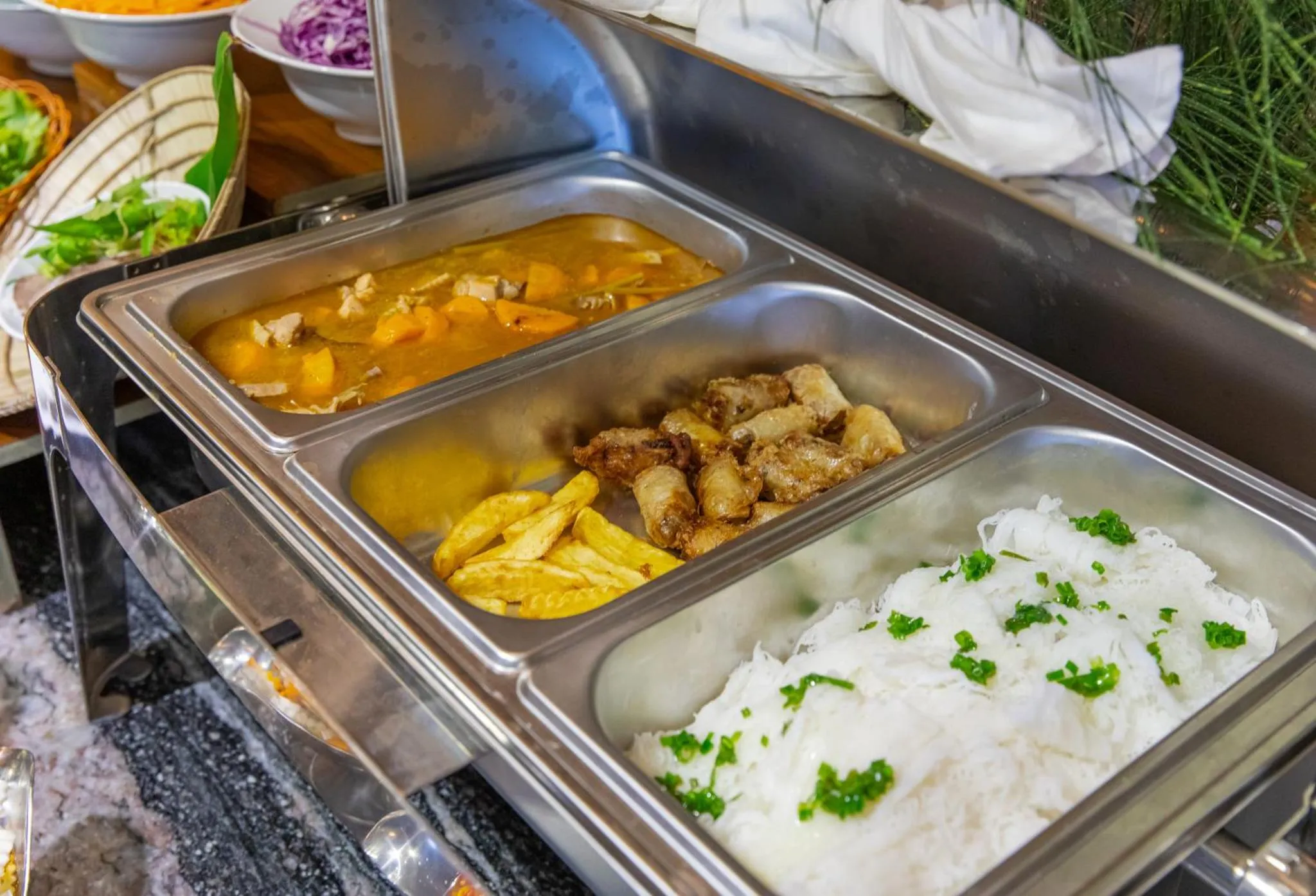 Présentation de plats variés dans des bacs en inox sur un buffet.